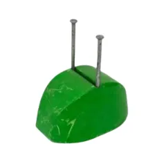 A green rubber anchor with two metal pins protruding from the top, used in construction for securing materials